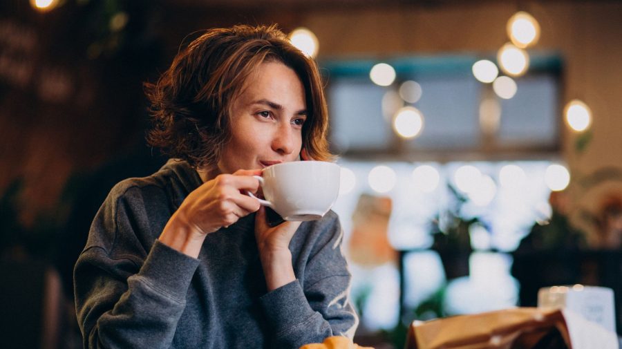 Žena pije v kaviarni kávu.