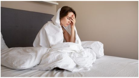 Žena v posteli sa drží za hlavu