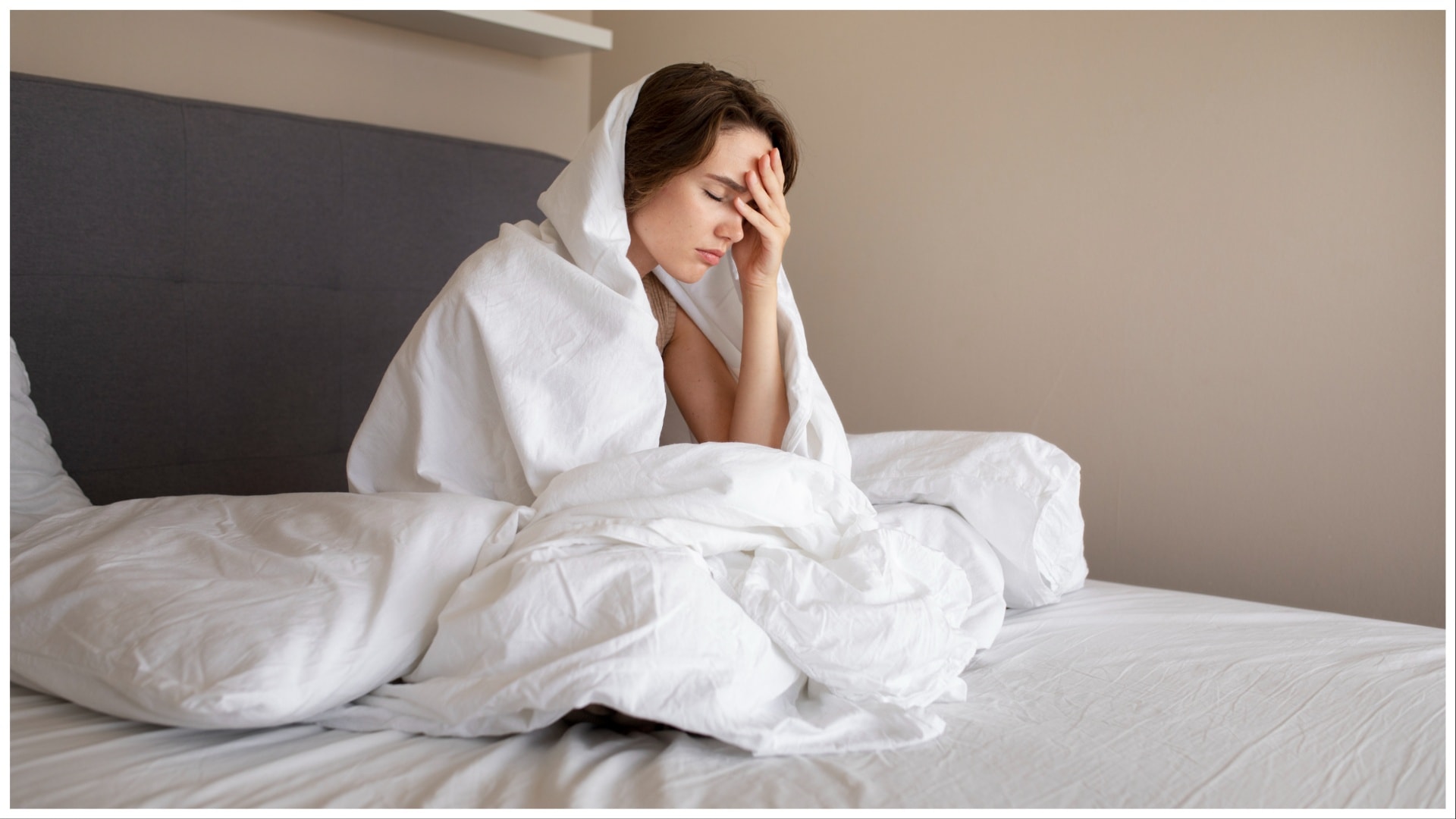 Žena v posteli sa drží za hlavu