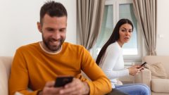 muž a žena v obývačke s mobilom v ruke