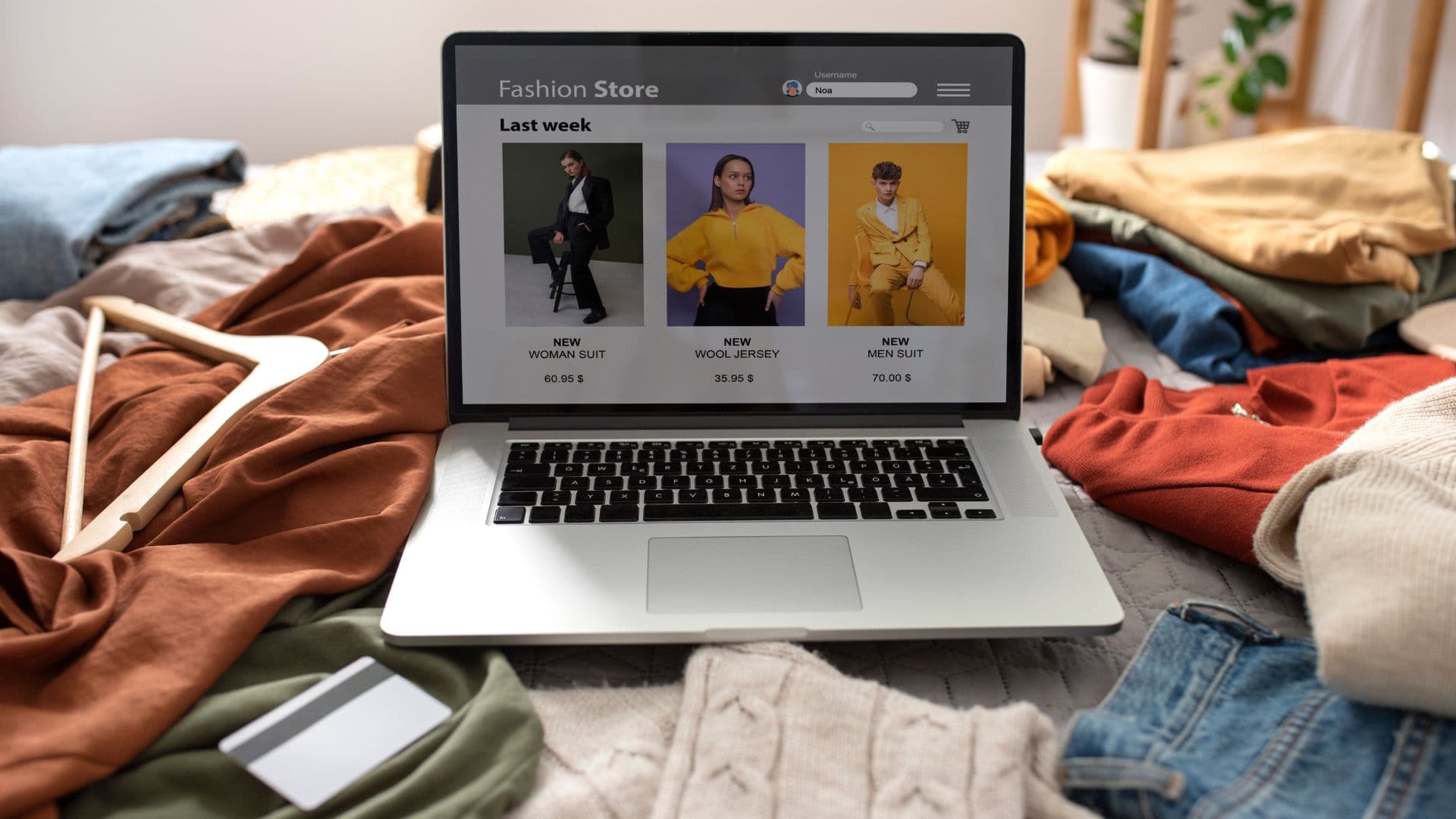 Notebook na posteli plnej oblečenia.