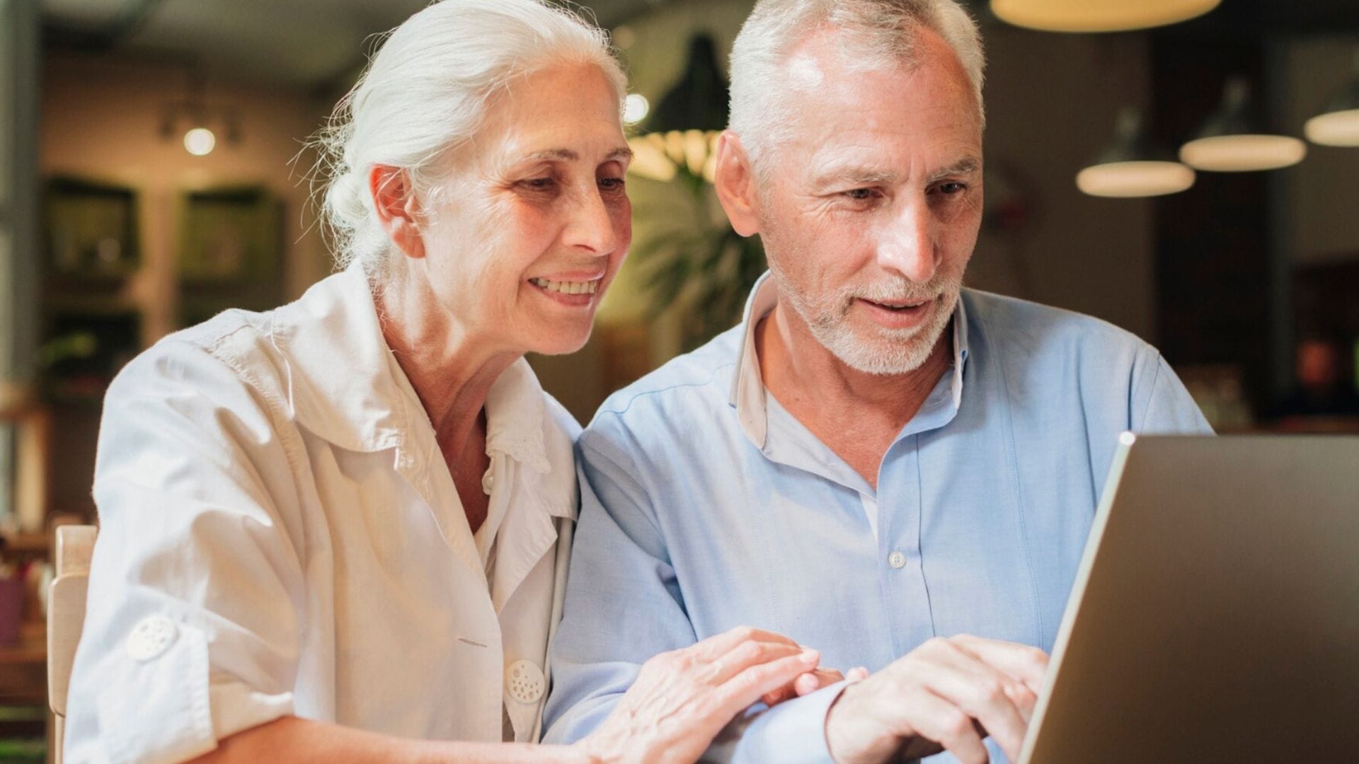 Starší muž a žena pozerajú do notebooku.