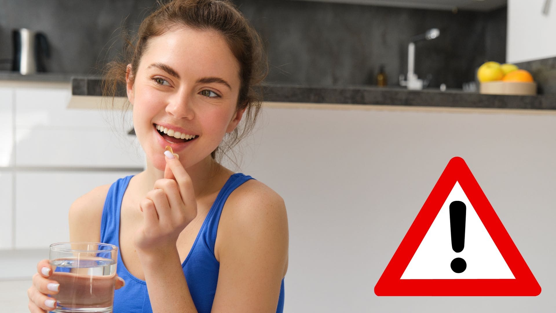 Žena drží pohár s vodou a do úst si vkládá vitamín.