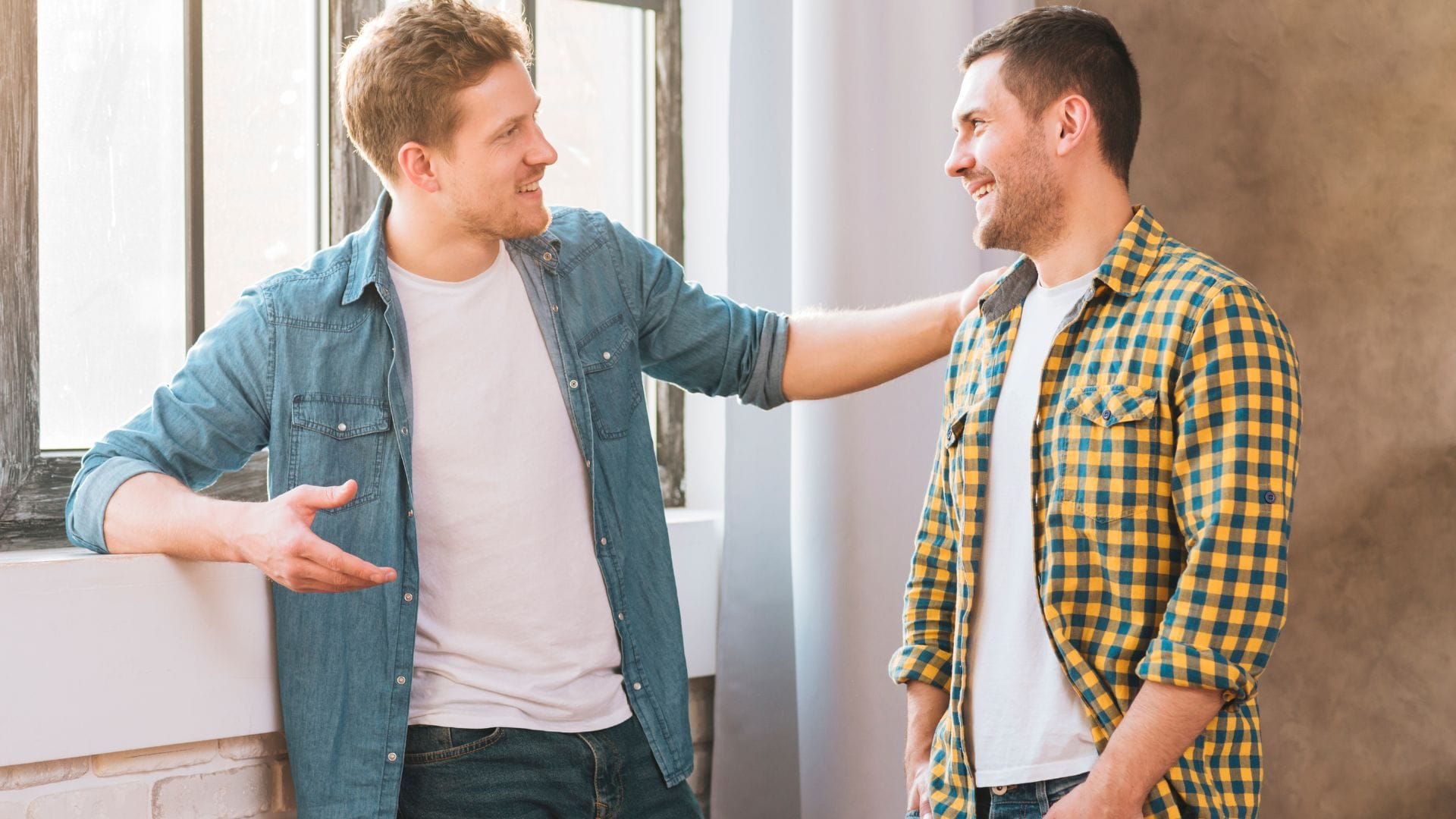 Dvaja muži sa zhovárajú pri okne.