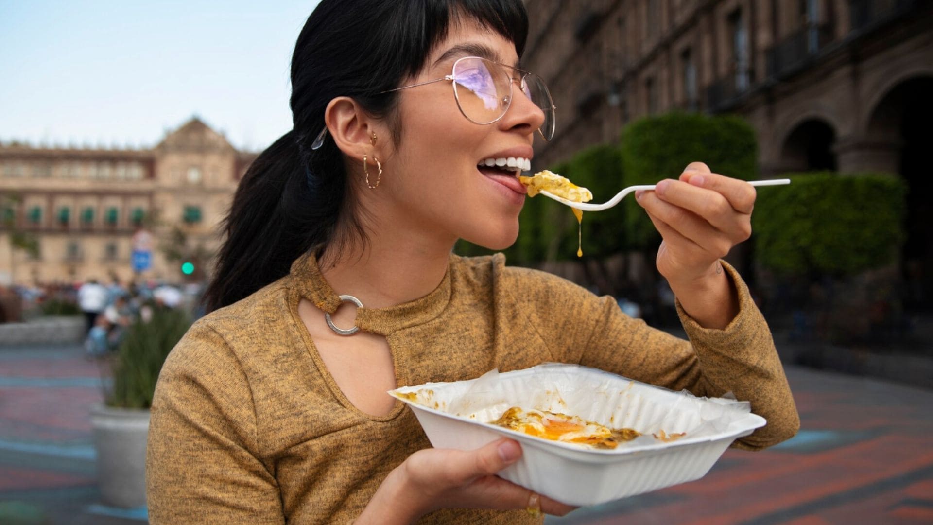 Žena konzumuje jedlo s vidličkou.