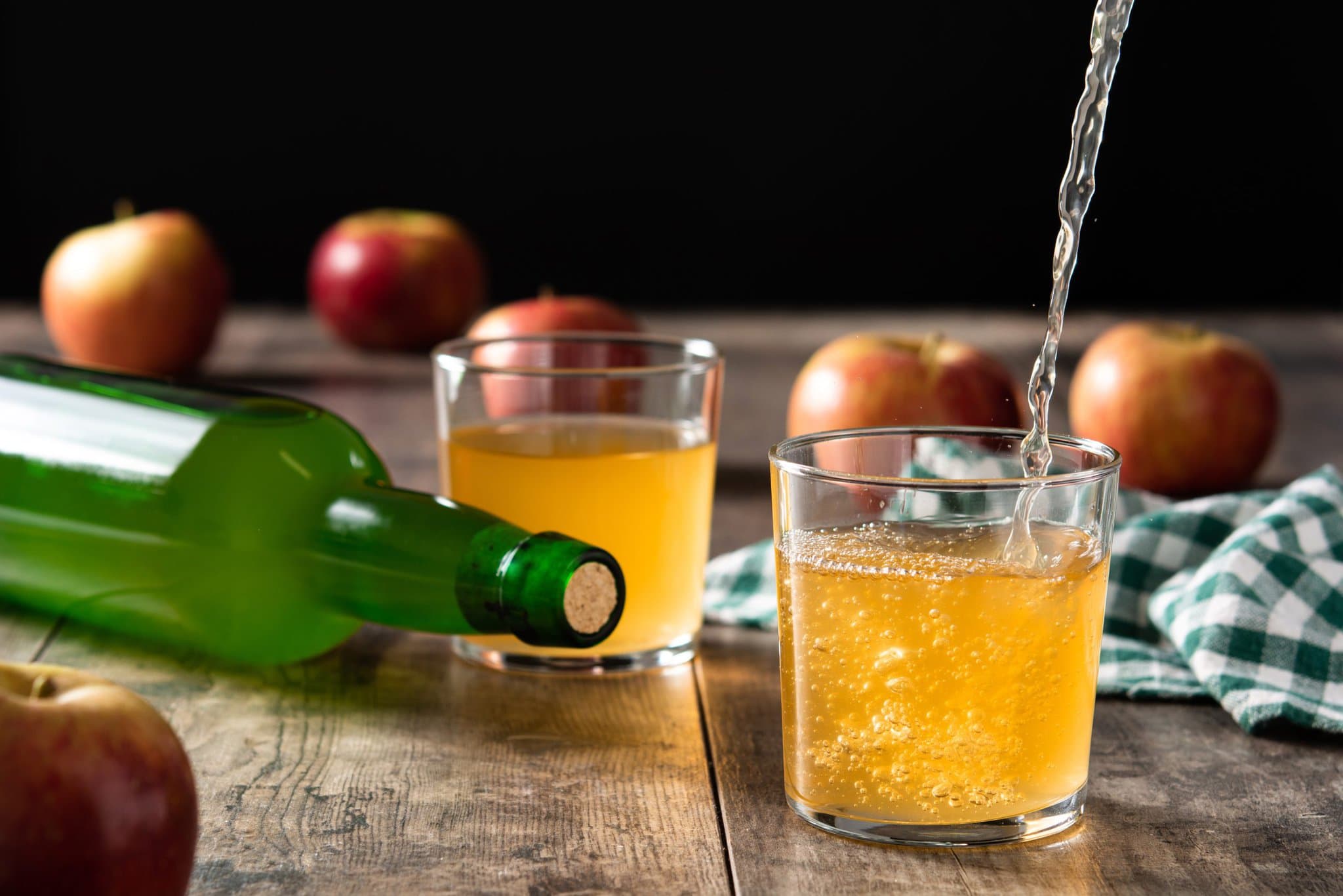 pouring-apple-cider-drink-into-glass-wooden-table