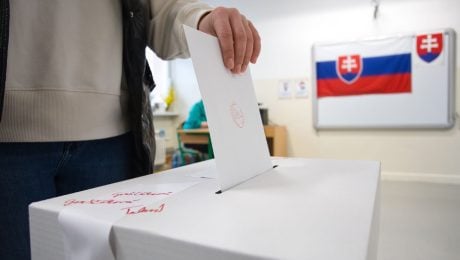 Muž vhadzuje do urny hlasovací lístok.