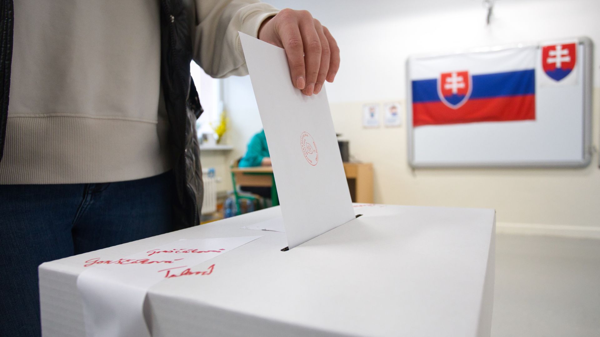 Muž vhadzuje do urny hlasovací lístok.