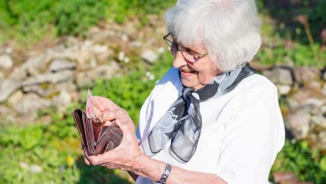 Dôchodkyňa si dáva peniaze do peňaženky.