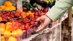 Ruka, ktoré berie dózičku s jahodami.