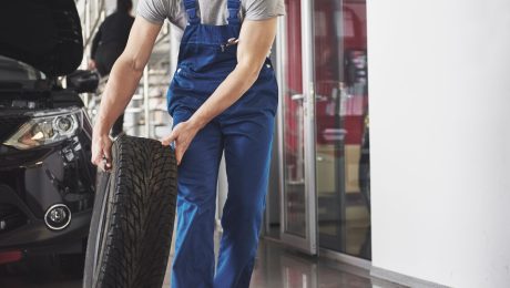Muž s pneumatikou v autoservise.