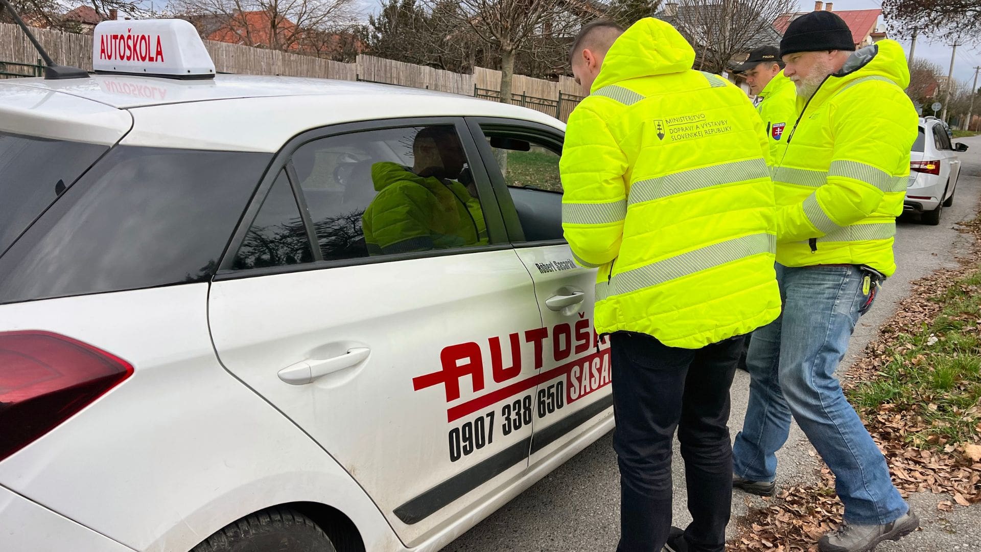 Inštruktori autoškoly pri vozidle.
