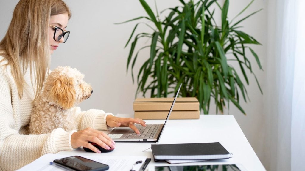 Zena pracuje na home office so psom na kolenách.