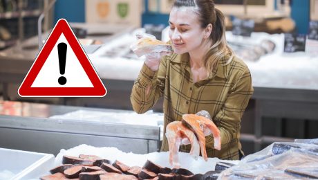 Žena drží lososa v rukách.