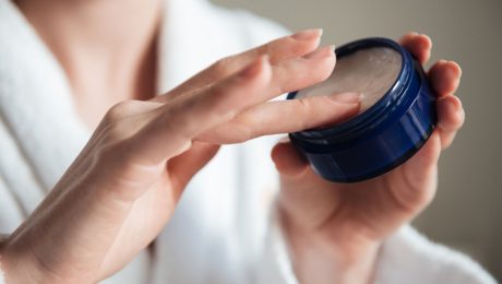 Žena si berie krém z nádobky.