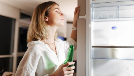 žena sa pozerá do chladničky a vyberá vodu