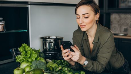 Žena drží v ruke mobil, zelenina, brokolica