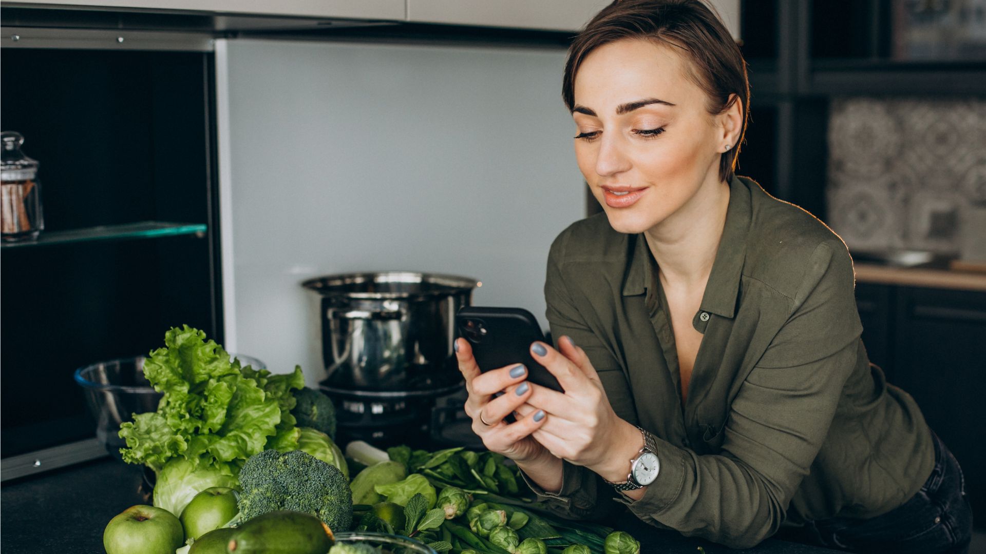 Žena drží v ruke mobil, zelenina, brokolica