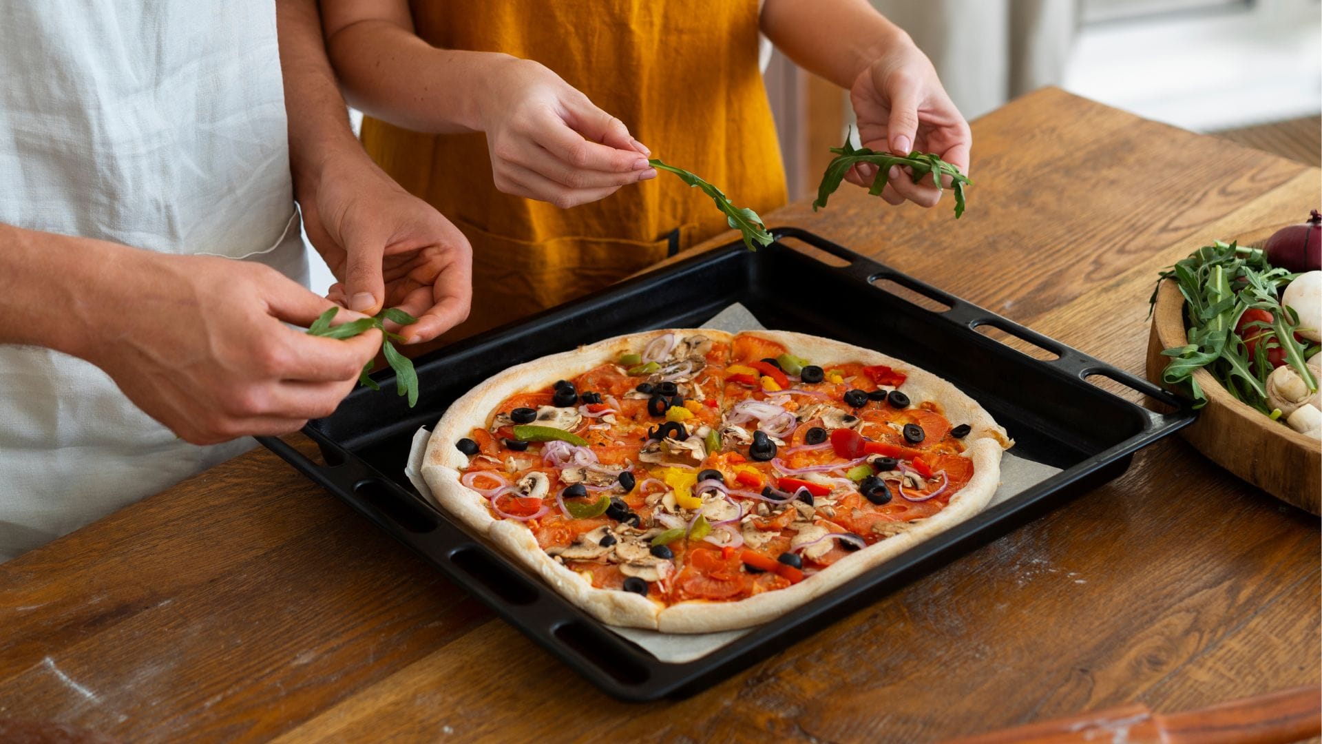 Dvojica pripravuje domácu pizzu so zeleninou a oreganom