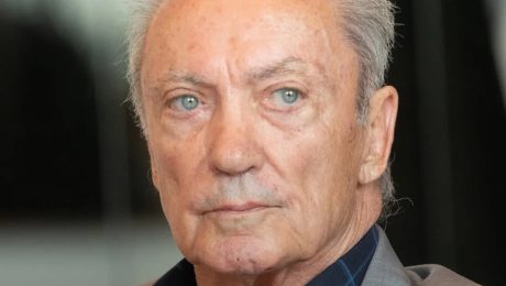 Starší muž s modrými očami, blízky portrét, na pozadí kancelária alebo interiér, profesionálne fotografie, téma biznis a leadership.