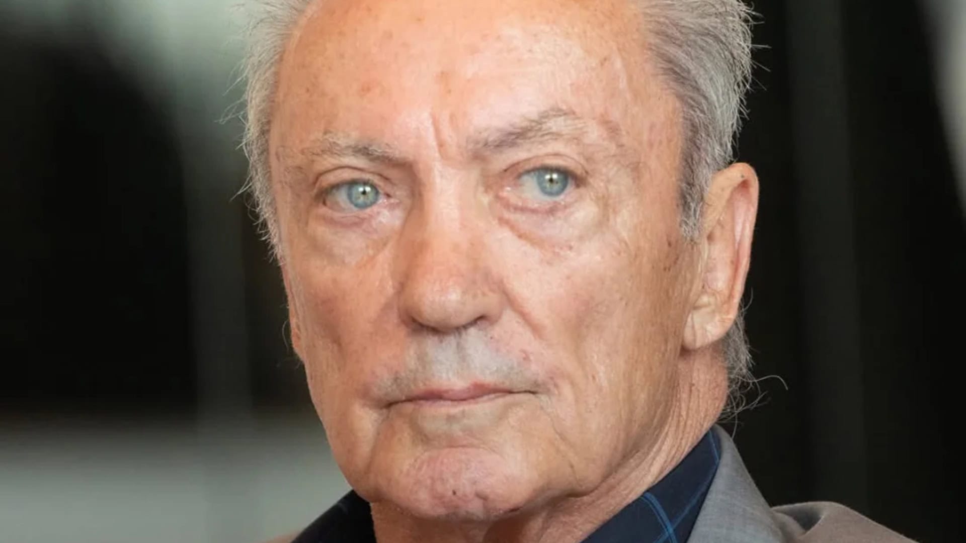 Starší muž s modrými očami, blízky portrét, na pozadí kancelária alebo interiér, profesionálne fotografie, téma biznis a leadership.