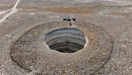 An aerial view of professional climbers descending into the approximately 40-meter-deep Inoba Sinkhole