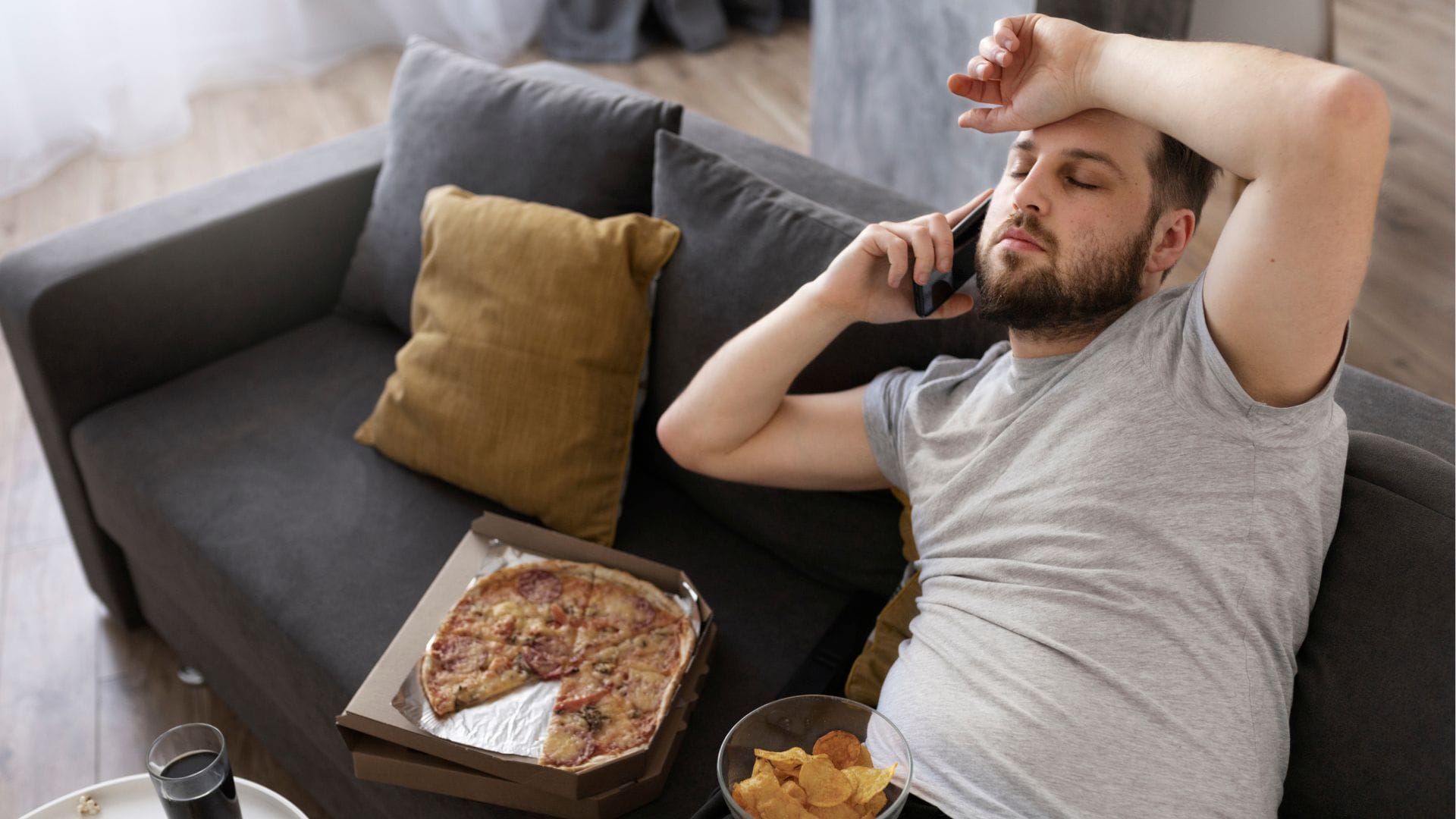 muž leží na gauči, pizza, chipsy