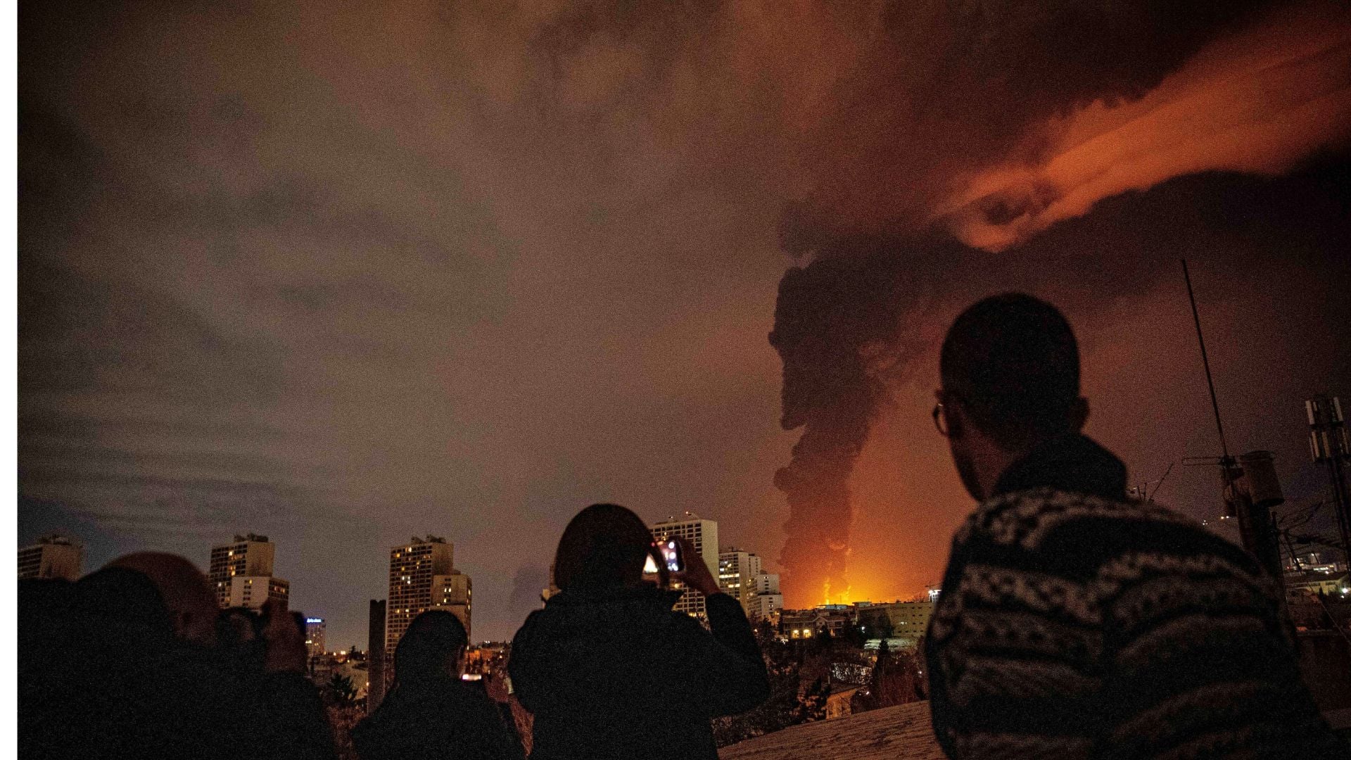 Obyvatelia sledujú a fotografujú plamene a dym stúpajúce zo zásobníka ropy, ktorý bol zasiahnutý útokmi na mesto počas americko-izraelskej vojenskej kampane v Teheráne v Iráne v