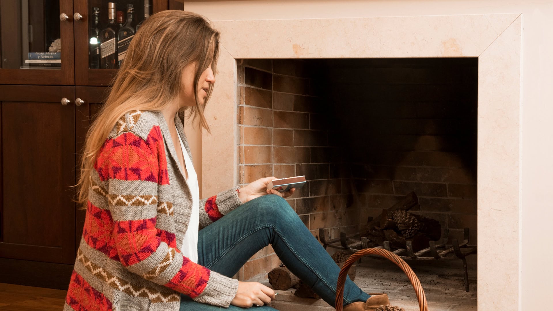 Na snímke žena sediaca pri krbe.
