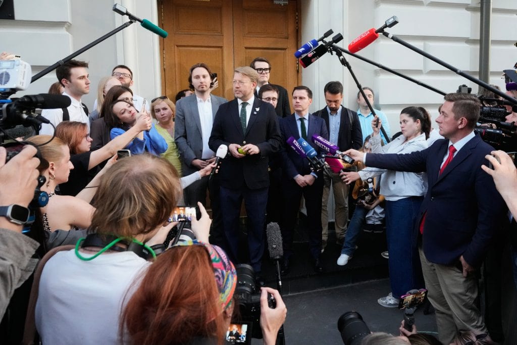Predseda strany Jabloko Nikolaj Rybakov (vpravo) a jeho právnik (druhý sprava) počúvajú súdne rozhodnutie odrazené v pohári po pojednávaní